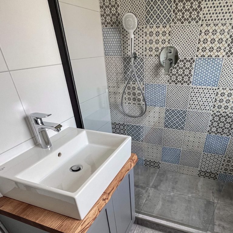 Badezimmer mit Waschbecken und Dusche und Mosaikfliese
